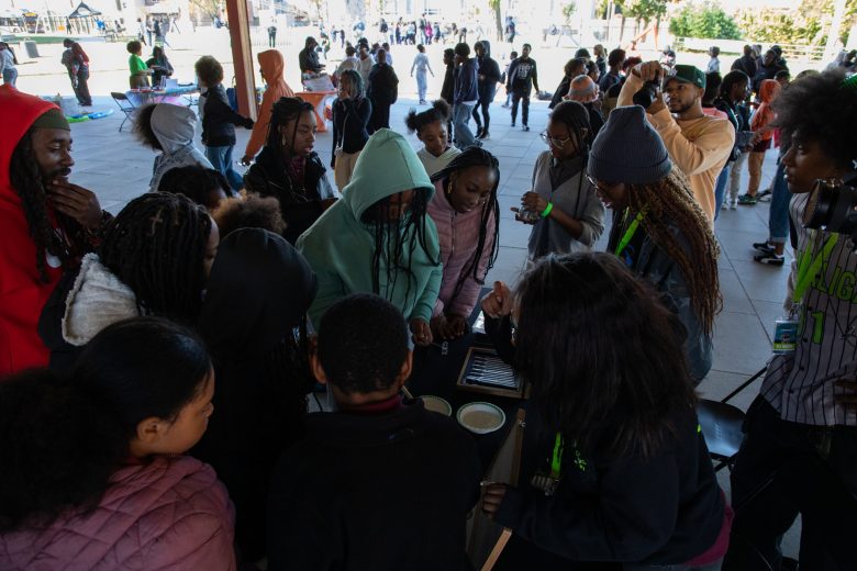 Students gather around the tuning fork station at the #STEAMtheBlock Party.