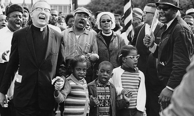 Martin Luther King Jr. was a champion for equity in education. Ralph Abernathy and his wife Juanita Abernathy (not pictured) follow with Dr. and Mrs. Martin Luther King, Jr., as the Abernathy children march on the front line, leading the Selma to Montgomery March in 1965. The children are (from left) Donzaleigh Abernathy (in striped sweater), Ralph David Abernathy III and Juandalynn R. Abernathy (in glasses). The name of the White minister in the photo is unknown. (Abernathy family photos/Wikipedia Commons)