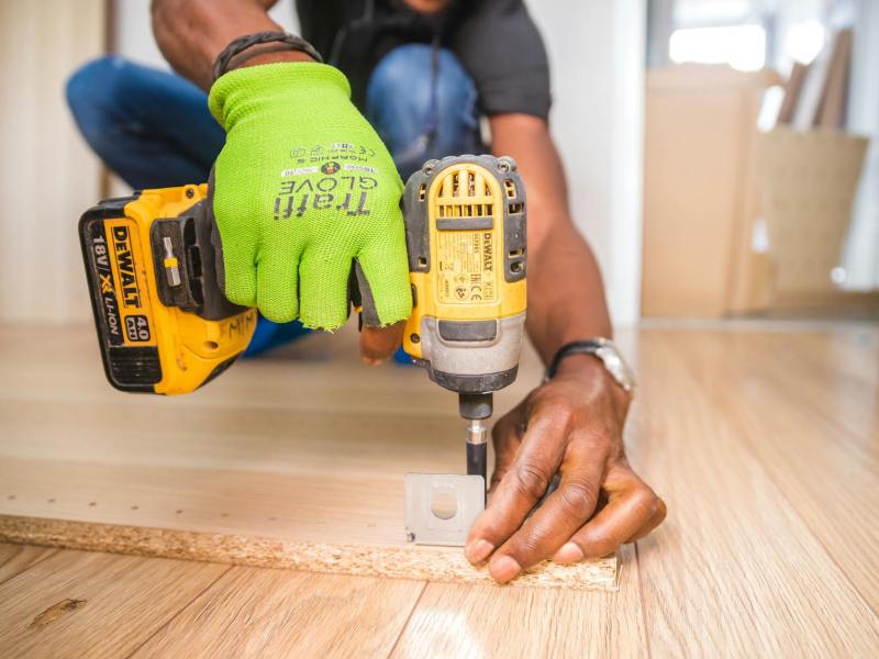 person using dewalt cordless impact driver on brown board