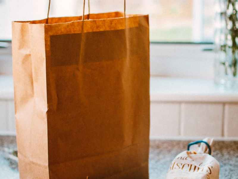 several apples beside bread pack and brown paper bag