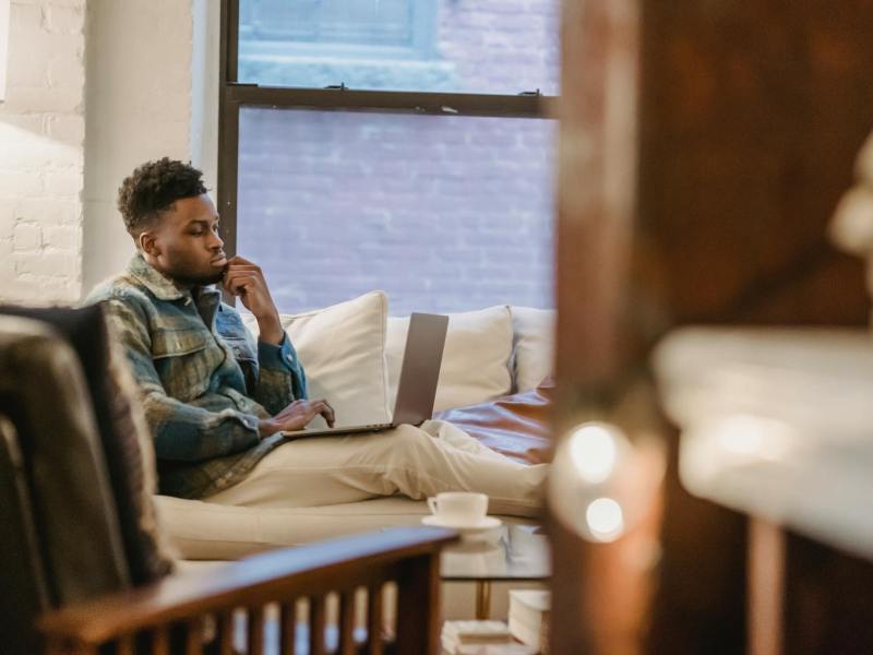 concentrated black man using laptop while sitting on couch