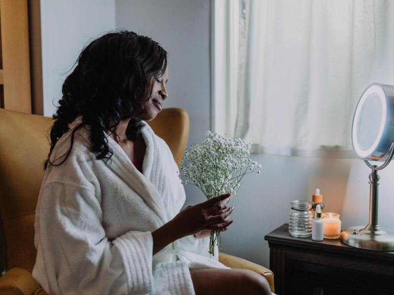 a woman wearing white robe holding a bunch of baby s breath flowers