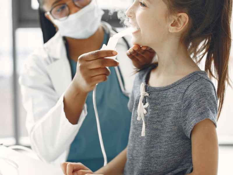a doctor giving medication to a girl through a nebulizer