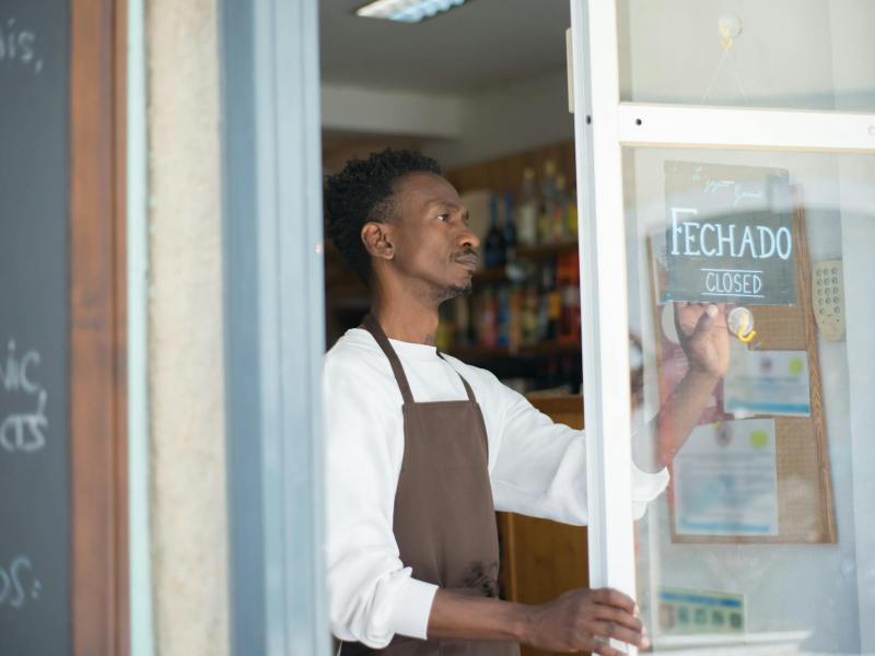 a man in white sweater and brown apron holding a signage